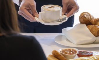 a man is serving a cup of coffee to a woman at a dining table at Dorsett Wanchai