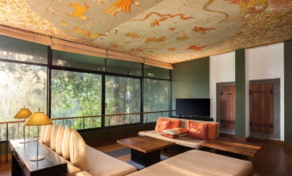 a spacious living room with a large flat - screen tv mounted on the wall , surrounded by couches and chairs at Heritance Kandalama