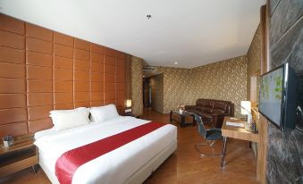 a modern bedroom with a large bed , red and white bedding , wooden flooring , and a brown leather chair at Pakons Prime Hotel