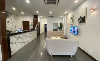 a modern office lobby with a white couch , marble wall , and a tv on the wall at Havona Hotel - Kulai