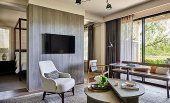 a living room with a chair , table , and large screen tv on the wall , along with dining table and window at Rosewood Sand Hill