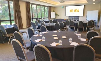 a conference room set up for a meeting , with tables and chairs arranged in rows at Sudima Auckland Airport