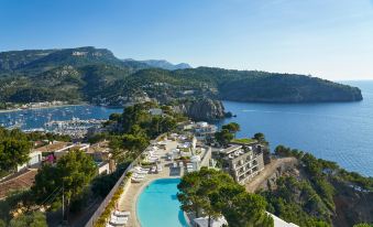 a beautiful resort with a large pool surrounded by trees and mountains , providing a serene view of the surrounding landscape at Jumeirah Mallorca