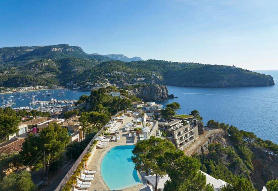 a resort with a large pool surrounded by lounge chairs and umbrellas , overlooking the ocean at Jumeirah Mallorca
