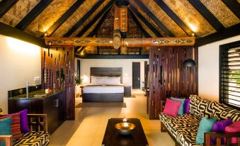 a luxurious bedroom with a large bed , a couch , and a tv . the room is well - decorated and appears to be inviting at Matamanoa Island Resort