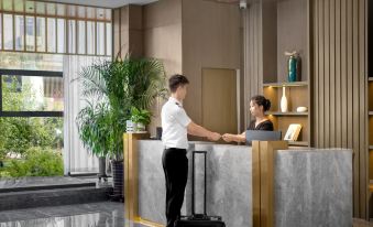 A woman stands in front of the airport counter while another person sits on top at Konggang Hotel (Harbin Airport International Terminal)