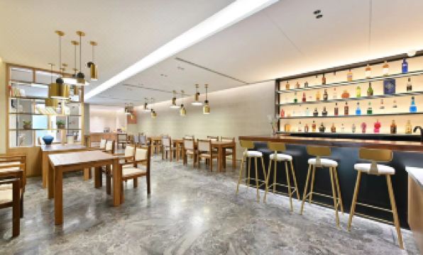 The restaurant has tables and chairs in the center, along with an open concept kitchen at Atour X Hotel Beijing Sanlitun Taikoo Li