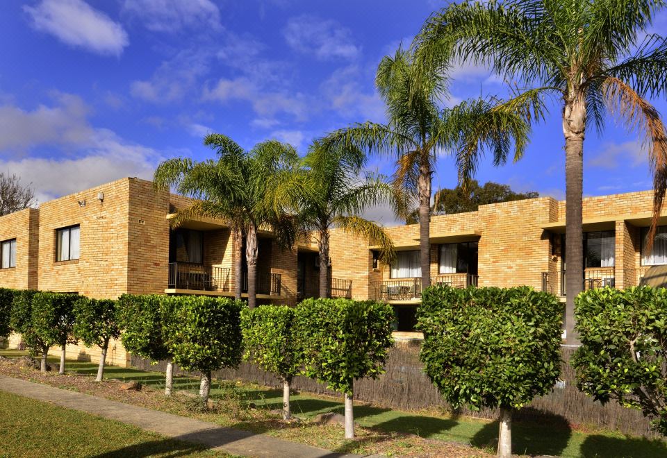 a large brick house surrounded by trees and bushes , located in a grassy area at Ryde Inn