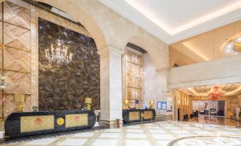 a large hotel lobby with a marble wall and a reception desk in the center at Regency Hotel