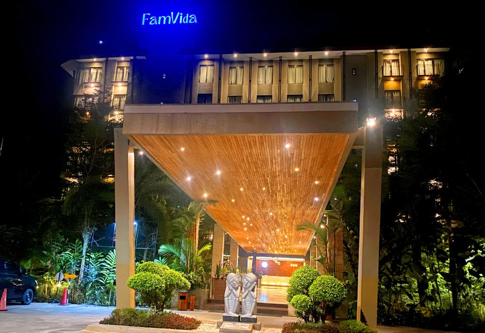 "a hotel entrance with a wooden canopy and the name "" faum arts "" on it , illuminated at night" at FamVida Hotel Lubuklinggau Powered by Archipelago