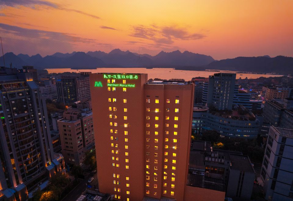 The city is illuminated by blue and red lights, creating a vibrant nighttime scene at Merchant Marco Hotel