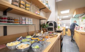 a kitchen counter with various food items and a variety of drinks , including cups , bottles , and bowls at Hotel Carlton