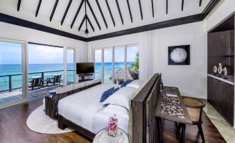 a bedroom with a large bed , white linens , and a view of the ocean through the windows at Naladhu Private Island Maldives