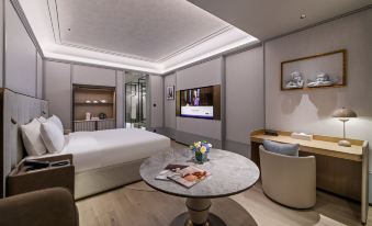 In the middle room, there is a large bed with a table and TV placed next to each other at Grand Mercure Hangzhou Zijingang