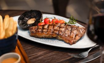 a plate of cooked meat and vegetables is served with a side of mushrooms and herbs at Holiday Inn Aylesbury