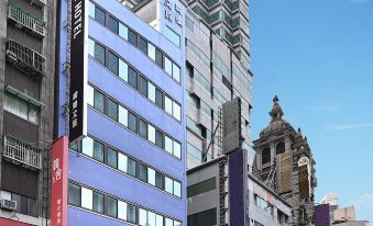 a city street with a tall building on the left side of the street , and a group of people standing in front of it at Le Room Hotel Taoyuan