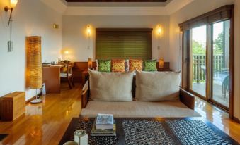 a spacious living room with a couch and dining table , as well as a balcony overlooking the ocean at Sankara Hotel & Spa Yakushima