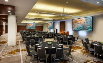 a large , well - lit conference room with multiple tables and chairs set up for an event at PARKROYAL Melbourne Airport