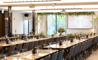 a long dining table with chairs is set up in a room with potted plants on the walls at The Marevo