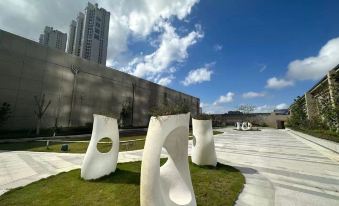 There is a park with grass and buildings in the background, featuring an artistic sculpture resembling something at Shantou Marriott Hotel