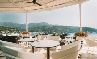 an outdoor dining area with white chairs and tables , overlooking a scenic view of mountains and water at Jumeirah Mallorca