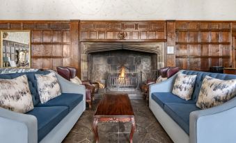 a cozy living room with a fireplace , two blue couches , and a wooden coffee table at Thurnham Hall