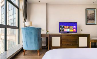 a bedroom with a bed , blue armchair , and a flat screen tv on a wooden desk at COMO