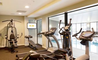 a gym with various exercise equipment , including treadmills and stationary bikes , is shown in a room with large windows at Sudima Auckland Airport
