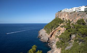 a cliffside with a white building on top and a body of water in the background at Jumeirah Mallorca