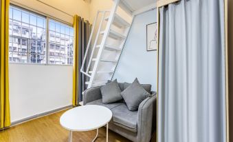 There is a living room with a couch and table in the middle, located next to a staircase leading upstairs at Yue City Youth Apartment