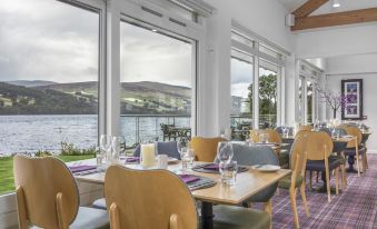 a dining room with a view of the lake , featuring tables and chairs arranged for a meal at The Kenmore Club