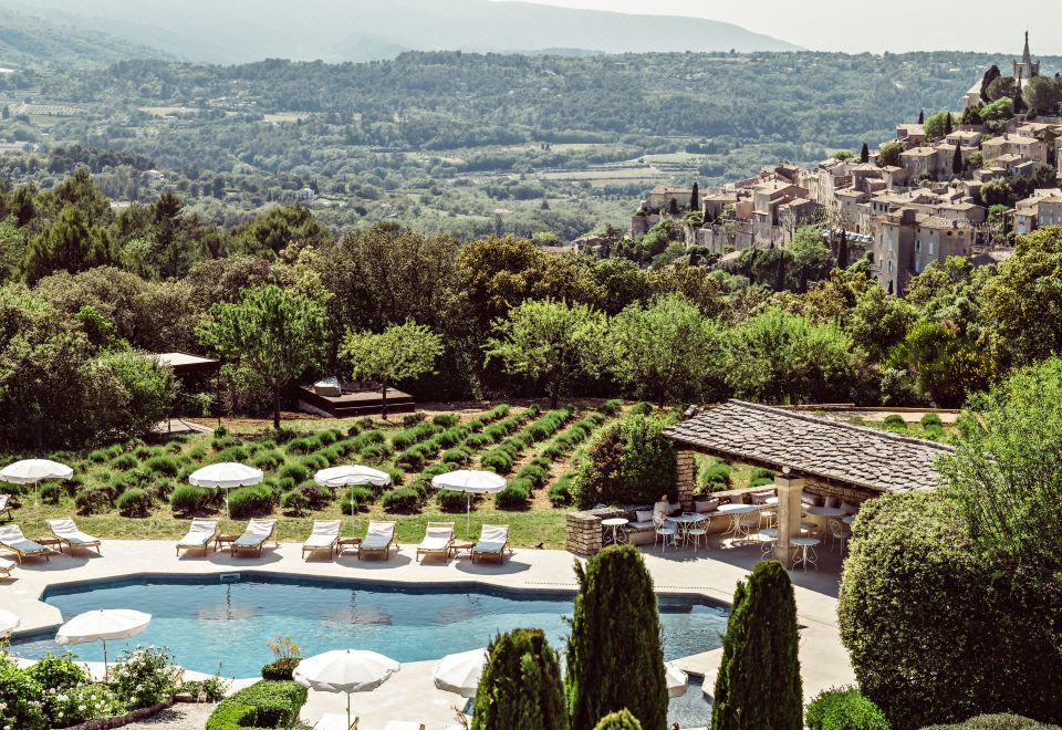 a resort with a large pool surrounded by lounge chairs and umbrellas , surrounded by lush greenery at Capelongue, a Beaumier Hotel & Spa