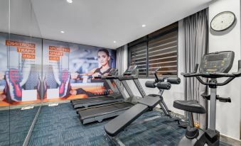 The living area of this home features a spacious room with an exercise bike and other equipment at Ausotel Smart Guangzhou Baiyun International Airport Terminal 1