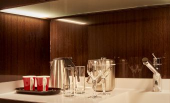 a kitchen counter with various items , including wine glasses , a toaster , and a kettle , along with a mirror above the sink at Park Plaza Westminster Bridge London