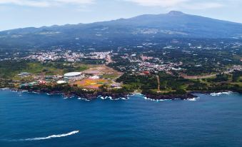 A large body of water is visible in the aerial view over the city and bay, with mountains in the background at Hotel the Grang Jungmun