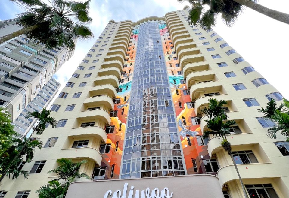 A tall building with numerous windows is located next to a large white sign at Coliwoo Orchard - Co-Living Serviced Apartments