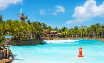 a large body of water with a boat docked on the shore , surrounded by palm trees at Disney's Pop Century Resort - Classic Years