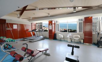 In the gym, there are large windows and various pieces of equipment, including an exercise machine at Qingdao  Litian Hotel