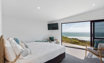 a large bed with white sheets and pillows is in a room with a sliding glass door leading to a balcony at Castaways Resort