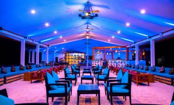 a large room with multiple tables and chairs arranged in rows , illuminated by blue lights at South Palm Resort Maldives