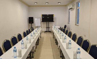 a long table with chairs is set up in a room with water bottles and a television on the wall at Chelsea Hotel