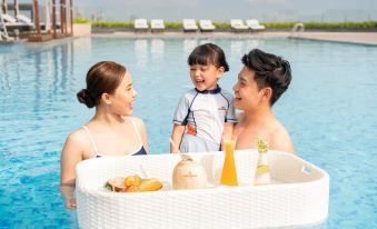 a family of three , consisting of a man , a woman , and a young boy , is enjoying a picnic by the side of a swimming at Sheraton Can Tho