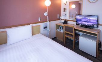 a hotel room with a white bed , a desk , a tv , and a chair , as well as a laptop on the desk at Toyoko Inn Aizuwakamatsu Ekimae