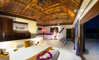 a man in a white robe standing in a room with wooden floors and a high ceiling at Navutu Stars Resort