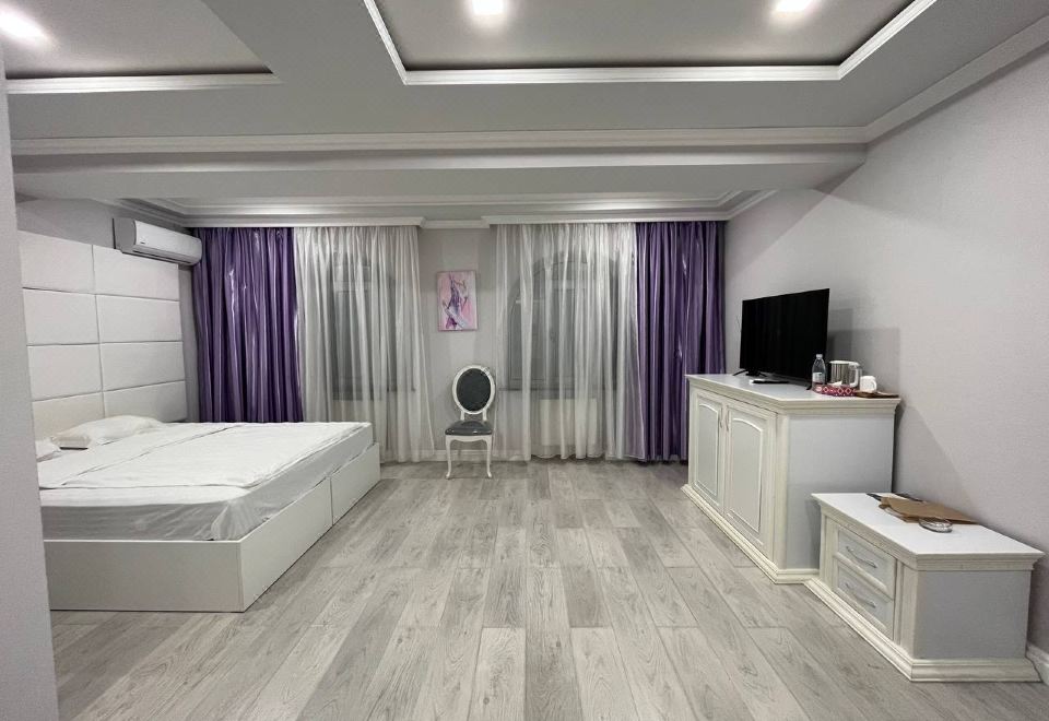 a modern bedroom with wooden floors , white walls , and a large bed , along with a tv and other furniture at Grand House hotel & zipline