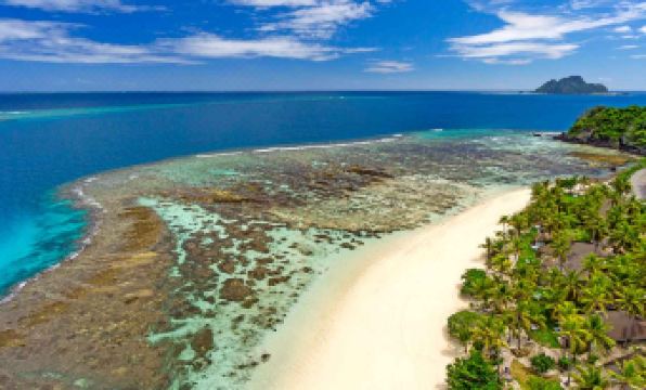a scenic aerial view of a sandy beach surrounded by coral reefs and blue ocean at Matamanoa Island Resort