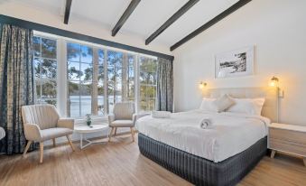 a large bed with white linens is situated in a room with wooden floors and a window overlooking a lake at The Fox and Hounds Historic Hotel