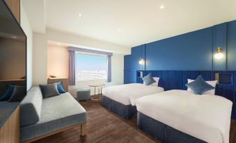 a hotel room with two beds , a couch , and a window , all decorated in blue and white colors at Oriental Hotel Tokyo Bay