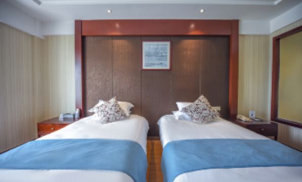 A bedroom on the left side features two double beds and a blue bedspread at Huachen San Siro Hotel