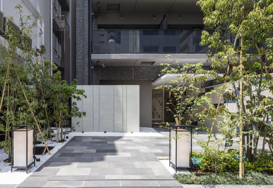 There is a courtyard with trees and plants located in front of the entrance to an apartment at Stayat Osaka Shinsaibashi East